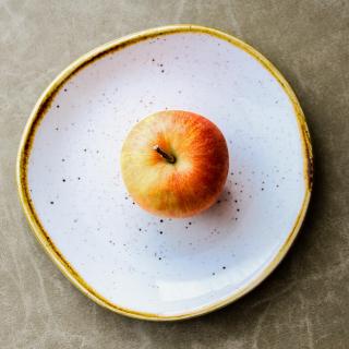 A red apple, from above, on a white plate.