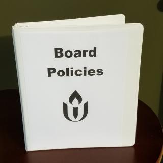 A binder marked board policies with a UUA chalice