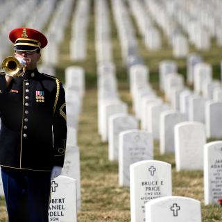 Army soldier in dress uniform playing Taps at Arlington National Cemetery