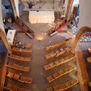 an aerial view of a church nave, with empty seats, undergoing renovation
