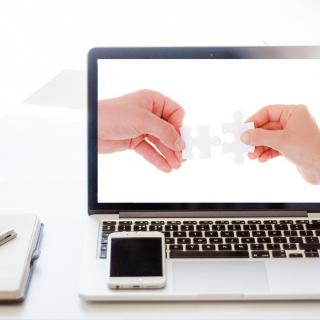 Laptop screen showing two hands matching a puzzle piece