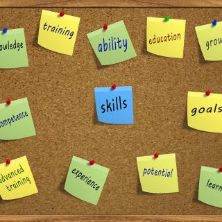cork board with 12 small square notes attached with pushpins. Each note has a word about work performance, such as goals, growth, and competence.