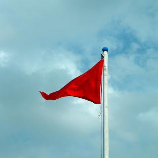 Red flag against cloudy sky
