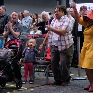 A family dances together in the aisle of the main hall, during worship