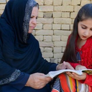 UNHCR Nansen Refugee Award Winner Aqeela Asifi helping a girl read.