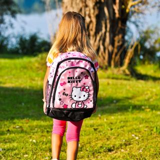 A young girl wears a large pink Hello Kitty backpack, in this photo taken from behind.