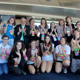 UUA President stands with a group of youth holding up their hands in the shape of a chalice.