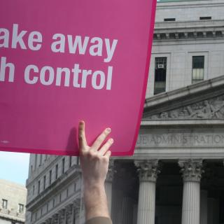 hands holding a sign that says "Don't take away my birth control"