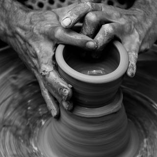 two hands are shaping clay on a pottery wheel