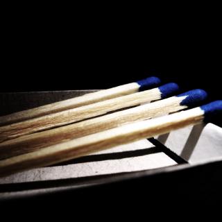 Four blue-tipped matches, resting on the edge of a box.