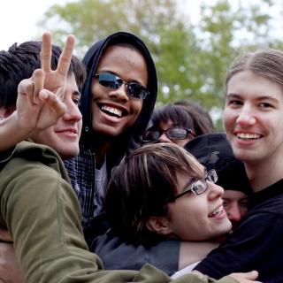 A group of smiling young adults hug.